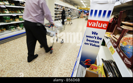 Tesco Value: un imprenditore con carrello camminando per un corridoio refrigerato di pizza e pasta. Foto Stock