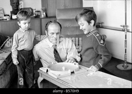 British boxer Henry Cooper nella foto con figli Henry Marco di età compresa tra i 10 (a destra) e 3 anni Giovanni Pietro giocando con una sommità di filatura gioco presso la sua casa di Wembley. Dicembre 1970 ;70-11690-002 Foto Stock