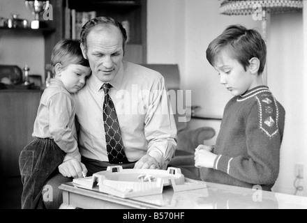 British boxer Henry Cooper nella foto con figli Henry Marco di età compresa tra i 10 (a destra) e 3 anni Giovanni Pietro giocando con una sommità di filatura gioco presso la sua casa di Wembley. Dicembre 1970 ;70-11690 Foto Stock