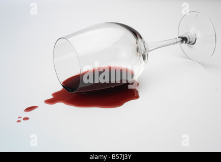 Ha versato un bicchiere di vino rosso su sfondo bianco Foto Stock
