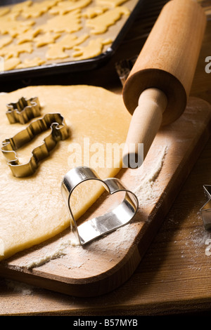 La cottura biscotti di Natale con amore - a forma di cuore ad cookie cutter, pasta laminata, mattarello, materie cookie sul forno cremagliera Foto Stock