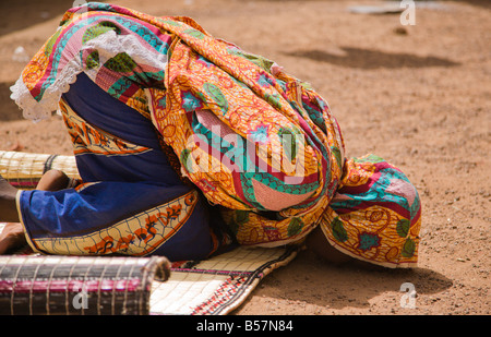 Una giovane donna Fulani in Ouagadougou Burkina Faso tocca la fronte a terra per la preghiera del pomeriggio Foto Stock