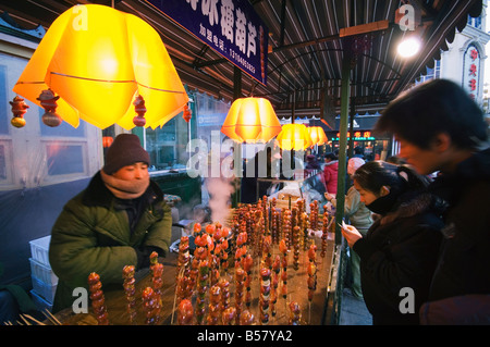 Una strada del mercato vendono spuntini locali e il dolce hawthorne su bastoni, area Daoliqu, Harbin, Provincia di Heilongjiang, Cina Foto Stock
