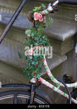 Vecchia bicicletta con fiori in appoggio contro scalini di pietra, Amsterdam, Paesi Bassi, Europa Foto Stock