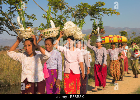 La gente che camminava per Monastero offerte di trasporto sulle loro teste, monaco novizio cerimonia, Lago Inle, Stato Shan, Myanmar (Birmania) Foto Stock