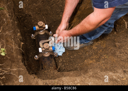 Uomo al lavoro su tubi sotterranei d'acqua Foto Stock