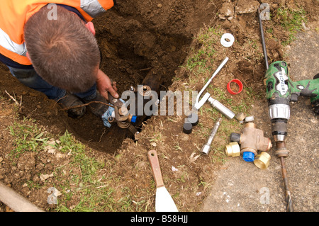 Uomo al lavoro su tubi sotterranei d'acqua Foto Stock