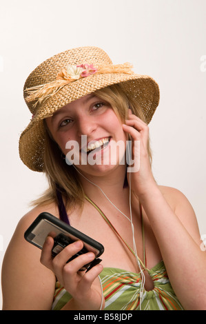 Donna che indossa cappello di paglia e vestiti estivi ascoltando la sua musica su iPod touch Foto Stock