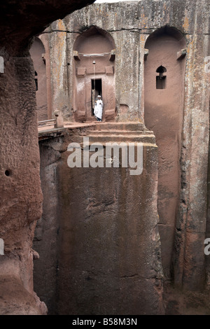 Un sacerdote si trova all'ingresso del rock-scavato nella chiesa di scommessa Gabriel-Rufael, in Lalibela, Etiopia, Africa Foto Stock