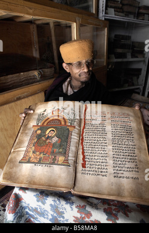 Un sacerdote passa attraverso un antico manoscritto presso il monastero di Kebran Gabriel, su un isola del Lago Tana, Etiopia, Africa Foto Stock