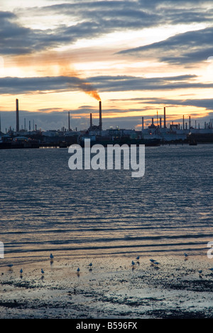 Fawley raffineria di petrolio su acqua di Southampton, Hampshire, Inghilterra al crepuscolo Foto Stock