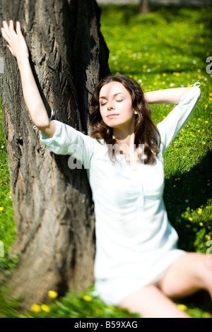 Giovane donna rilassante sotto agli alberi Foto Stock