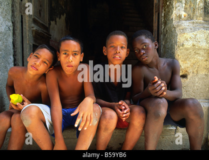 I ragazzi appendere fuori in uno stipite della porta nella antica citta' coloniale di Havana, Cuba Foto Stock