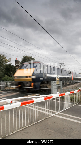 Treno ad alta velocità presso un passaggio a livello Foto Stock