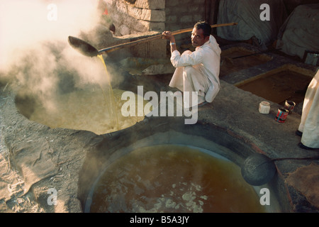 Bollire acqua dal succo di canna per rendere lo zucchero jaggery dopo la canna da zucchero raccolto nello Stato di Gujarat India Asia Foto Stock