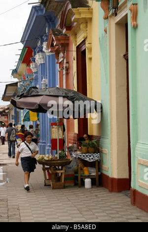 Scuola nicaraguense ragazza camminare lungo il marciapiede passato colorato facciate di edifici in stile coloniale spagnolo della città di Granada, Nicaragua Foto Stock