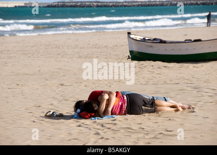 Paio di dormire su una spiaggia con barche di legno su Playa Malvarrosa nella città di Valencia Spagna Foto Stock