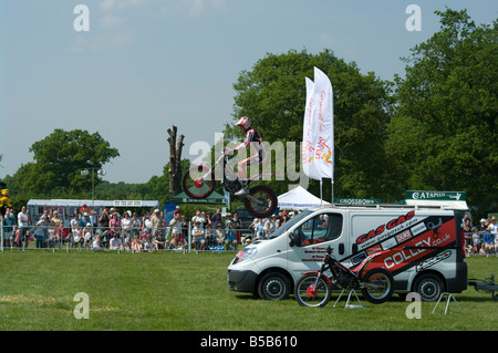 Motociclista acrobatico equitazione sulla sua moto saltando su un veicolo Cowpie Rally Betchworth Surrey eseguono acrobazie Foto Stock