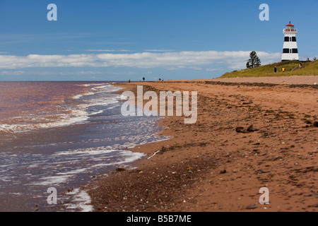 Lavare le onde sulla riva di fronte al West Point Lighthouse sulla spiaggia a Prince Edward Island, Canada. Foto Stock