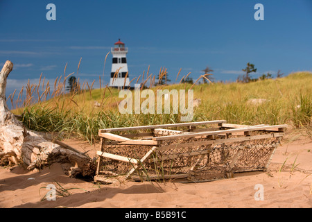 Un abbandonato trappola di aragosta si siede di fronte a West Point Lighthouse sulla spiaggia a Prince Edward Island, Canada. Foto Stock