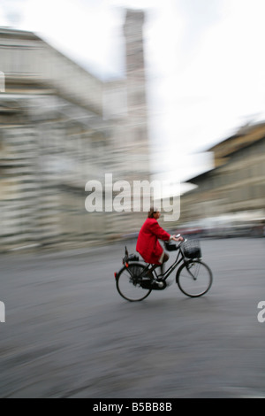 Donna ciclista in rosso rivestire passando per il Duomo di Firenze (Italia). Foto Stock