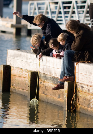 Famiglia seduta sul molo di pesca del granchio Foto Stock