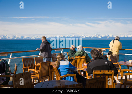 I passeggeri di crociera la visita sulla sala da pranzo esterna coperta la visione di montagne innevate sul passaggio interno di crociera in Alaska Foto Stock
