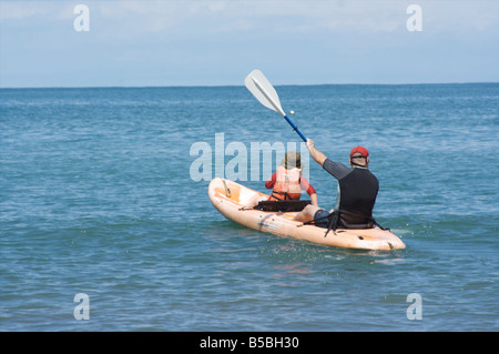 Un uomo e ragazzo paddling barca nell'oceano. Foto Stock