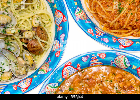 Tris di pasta italiana e di riso Spaghetti alle vongole Spaghetti con mix frutti di mare riso con calamari isolato su bianco Foto Stock