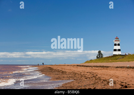 Lavare le onde sulla riva di fronte al West Point Lighthouse sulla spiaggia a Prince Edward Island, Canada. Foto Stock