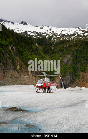 Il pilota e l'equipaggio dell'elicottero aiutano i turisti a scendere dall'elicottero sulla cima del ghiacciaio Mendenhall vicino a Juneau in Alaska Foto Stock