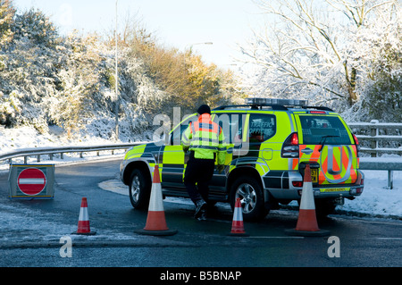 Highways Agency uomini vicino l'autostrada strada a scivolo nella neve a causa di un incidente Foto Stock