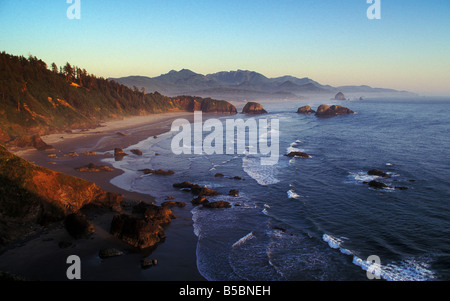 Vista della spiaggia a mezzaluna Cannon Beach Haystack Rock e la costa di abbracciare il punto da Ecola State Park al tramonto Oregon Foto Stock