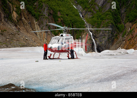 Il pilota e l'equipaggio dell'elicottero aiutano i turisti a scendere dall'elicottero sulla cima del ghiacciaio Mendenhall vicino a Juneau in Alaska Foto Stock