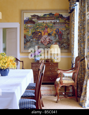 Grande immagine colorata sulla parete del giallo sala da pranzo con giallo Giunchiglie in vaso blu sul tavolo con un panno bianco Foto Stock