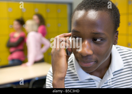 Ragazzo adolescente con il GSM in school hall Foto Stock