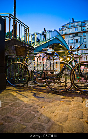 Underview di un ponte metallico con le biciclette in primo piano nel crepuscolo Foto Stock