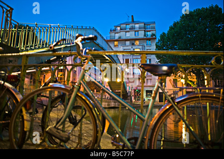 Underview di un ponte metallico con le biciclette in primo piano nel crepuscolo Foto Stock