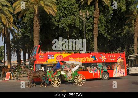 Un turista cavallo e carrozza (Caleche) con una gita in autobus dietro a un ingresso da Djemaa El Fna - la piazza del mercato di Marrakesh. Foto Stock