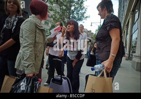 Un Chugger parlando agli acquirenti in Oxford Street London REGNO UNITO Foto Stock