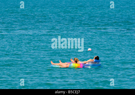 Un giovane su due materassini gonfiabili galleggianti in oceano Arabico, Ras Al Khaimah Emirati arabi uniti Foto Stock