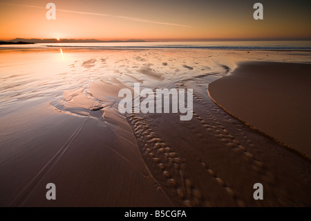 Il sole tramonta dietro l'Isola di Skye come visto dal Redpoint spiaggia vicino a Gairloch, Rossshire, Scozia Foto Stock