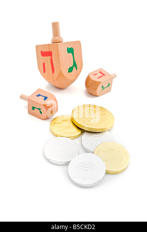 Tre dreidel in legno e monete di cioccolato gelt jewish hanukkah gioco isolato su bianco Foto Stock