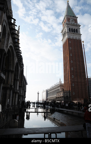 Allagamento di Piazza San Marco, Venezia, durante l'alta marea. I turisti in coda fino a visitare San Marco su schede di anatra. Foto Stock