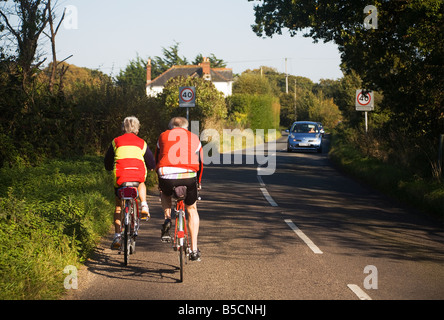 Adulti attivi. Coppia matura in bicicletta lungo una strada di campagna al confine di Hampshire e Dorset. Regno Unito. Foto Stock