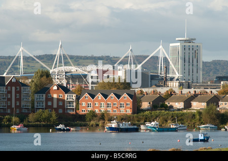 Barche ormeggiate vicino waterside case e case con Cardiff City skyline visto dalla baia con il Millennium Stadium, Wales UK Foto Stock