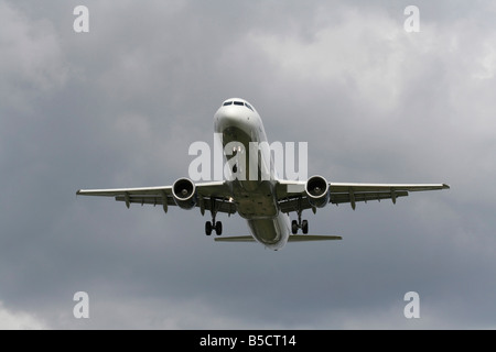 Il viaggio in aereo. Airbus A321 aereo commerciale che arrivano in un cielo nuvoloso. Vista anteriore con nessun livrea e dettagli proprietario eliminati. Aviazione moderna. Foto Stock