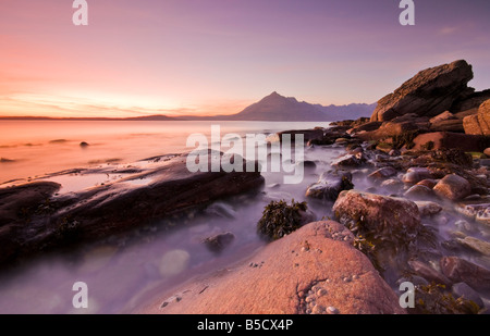 Il sole tramonta dietro il Cuillin Range di montagna come visto dal Elgol sull'Isola di Skye in Scozia UK Foto Stock