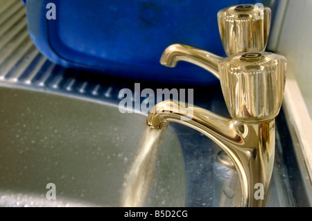 Esecuzione di acqua da un rubinetto al lavello. Foto Stock