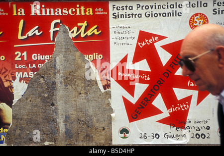 Passato interesse. Un uomo camminare davanti a un paio di vecchi fly-poster, non mostrando interesse per loro. Fotografato a Pisa, Italia. Foto Stock